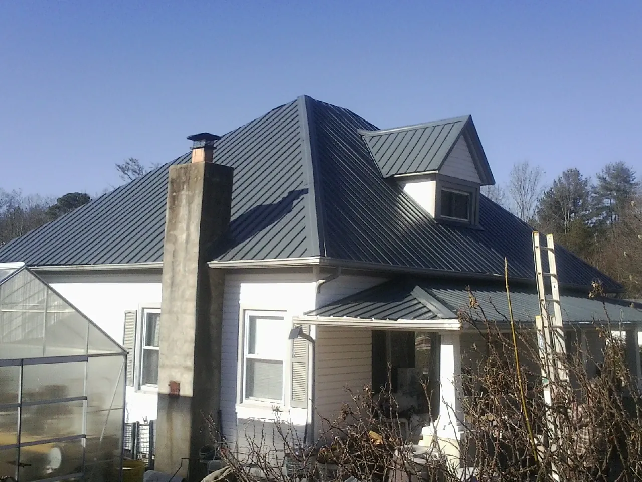 Dark blue standing seam metal roof on a white farmhouse with dormer — Slate & Tile Roof Repair by Roofing Brothers in Austell