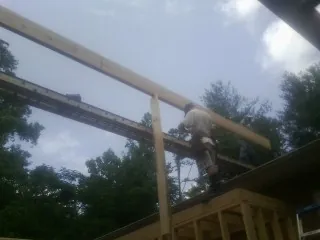 Carpenter setting a ridge beam over a new addition frame — Ice Dam Removal by Roofing Brothers in Austell