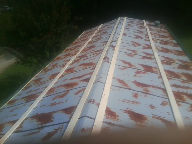 Rusted metal roof panels with new wood purlins before replacement — Storm Damage Roof Repair in Austell by Roofing Brothers