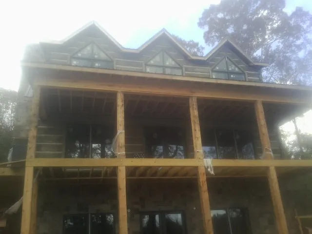 Dormers and porch framing on a large log home under construction — Roof Coating work by our crew in Austell