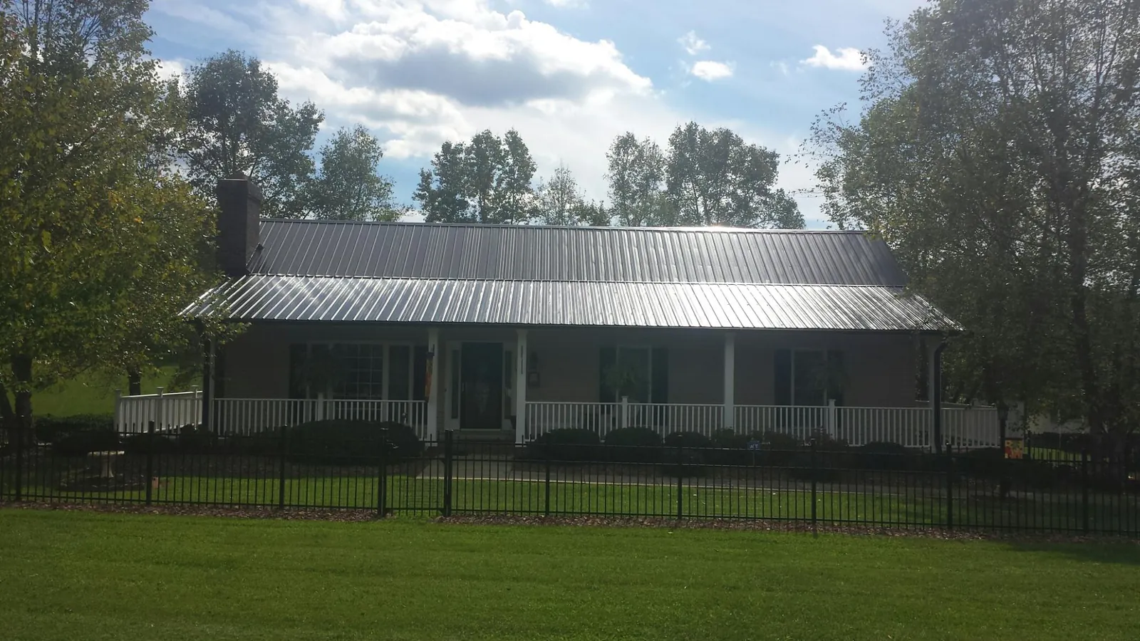 Gray metal roof on a brick ranch with a full width front porch — Gutter Guard Installation work by our crew in Austell