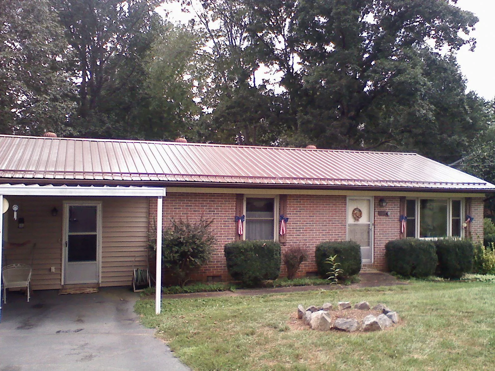 Bronze metal roof and carport on a brick ranch home — Roof Repair work by our crew in Austell