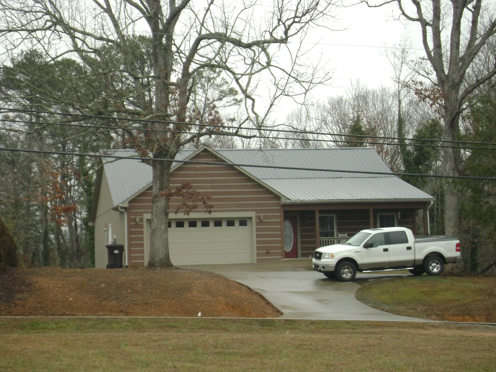 Gray metal roof on a log sided house with an attached two car garage in Austell
