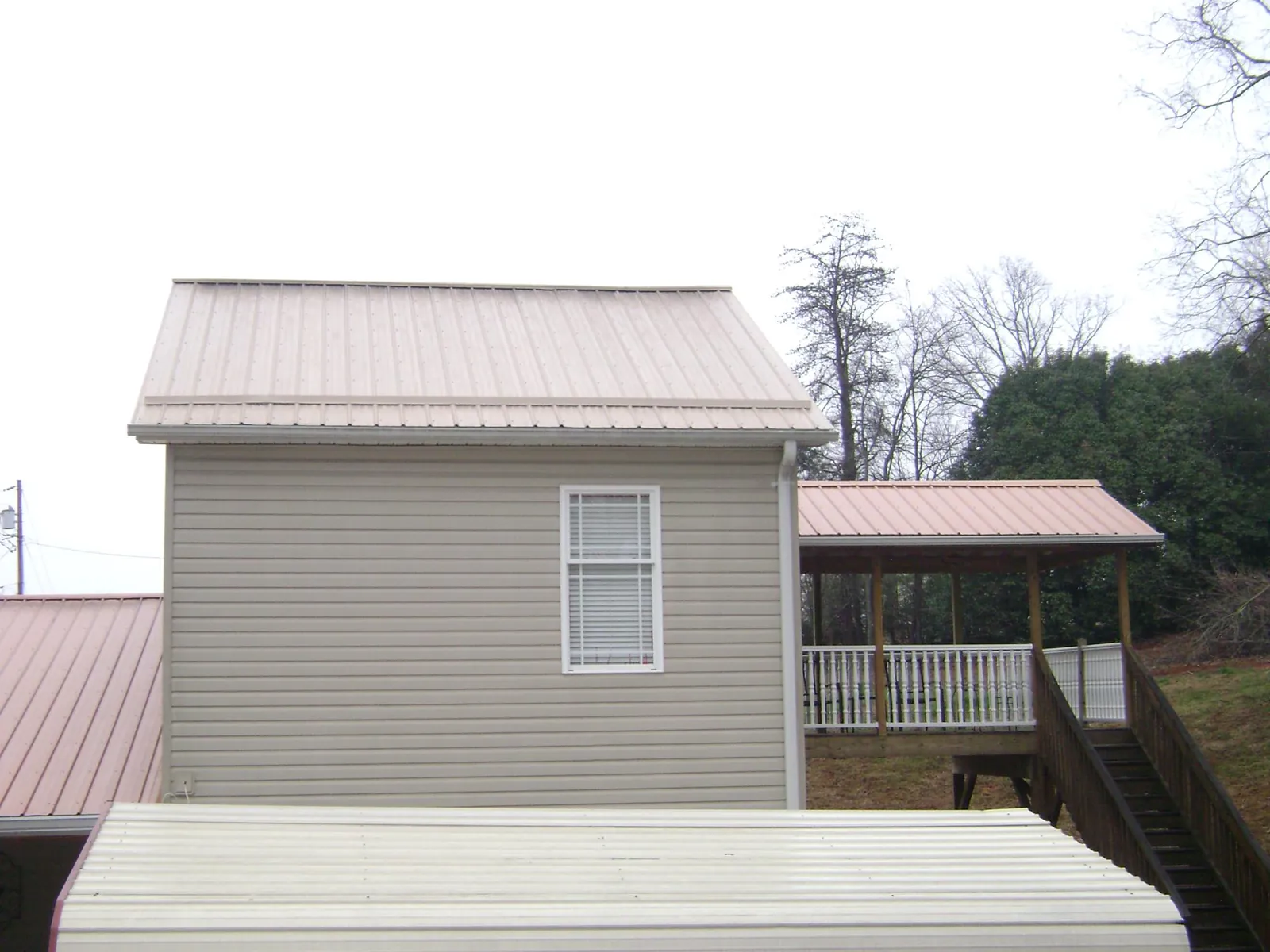 Tan metal roofs on a two story addition and attached porch, from a Roof Replacement job in Austell