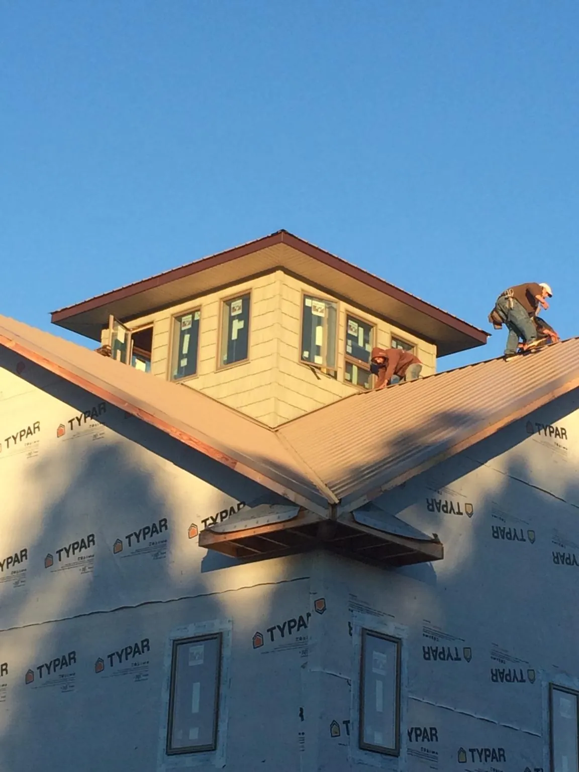 Roofers working around a rooftop cupola on a new metal roof at sunset — Roof Waterproofing in Austell by Roofing Brothers